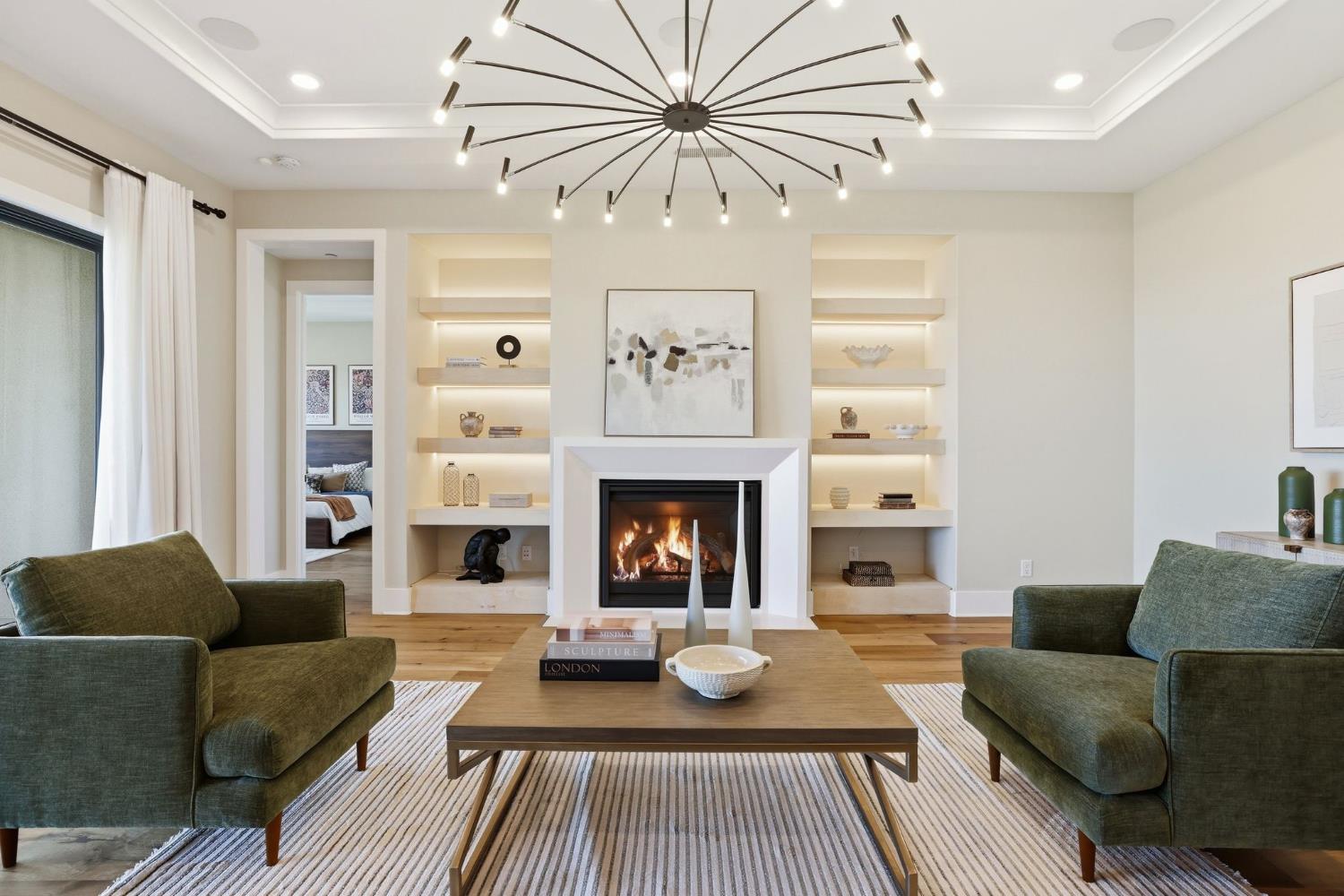 Living room with a fireplace, illuminated shelving, and two green armchairs