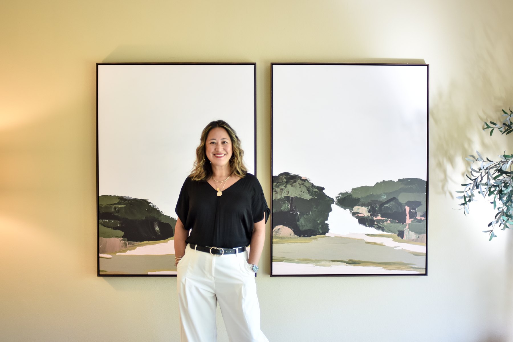 Erica Labson Aller standing beside two framed abstract paintings